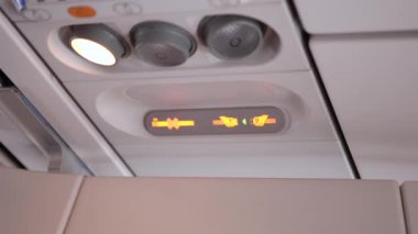 Emniyet kemerini gösteren ve uçuş sırasında sigara içilmemesi talimatlarını içeren bir uçak güvenlik panelinin kapatılması, seyahat güvenliği ve yönetmeliklerini vurguladı.