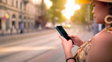 Budapeşte 'de bir tramvay istasyonunun yakınında akıllı bir telefonla konuşan şık bir kadın, şehir yaşam tarzını ve taşımacılığı sergiliyor..