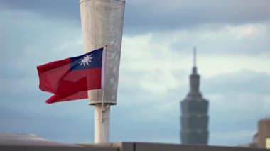 Tayvan ulusal bayrağının yavaşça dalgalanması arkadaki Taipei 101 ile bulutlu bir günde Taipei 'nin şehir siluetine karşı ulusal gururu sembolize ediyor..