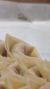Tayvanlı bir takım şefinin dikey yavaş hareketi geleneksel hamur köftelerini ustalıkla hazırlar, elleri hamuru ustalıkla şekillendirir. Kalabalık bir restoranda şefler taze ve otantik tatlar yaratıyor..