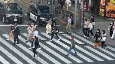 Tokyo, Japonya-13 Nisan 2023: Kuşların bakış açısı kavşakta trafik sinyalinin değişmesini bekleyen insanları gösteriyor. Kalabalık, etkileyici bir senkronizasyon ve verimlilikle ilerliyor..