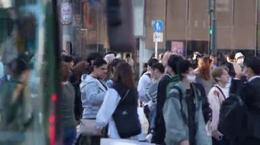 Tokyo, Japonya-10 Nisan 2023: Japonya 'da gündüz vakti ünlü Shibuya Geçidi' ni geçen kalabalık kalabalık, yoğun bir şekilde toplanmış ve hızla caddelerde ilerliyordu..