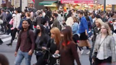Tokyo, Japonya-10 Nisan 2023: Gündüz saatleri, insanların Japonya 'da Shibuya Geçidi' nden geçerken şehrin canlı şehir yaşamını gözler önüne seren kesintisiz bir akışa tanıklık ediyor..