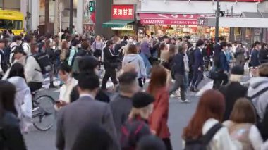 Tokyo, Japonya-10 Nisan 2023: Shibuya Geçidi 'nde yürüyen büyük bir kalabalık, hareketli metropolün çeşitliliğini gösteriyor. Herkes koşuşturmaca ve kalabalık içinde ilerler.