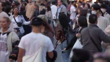 Tokyo, Japonya-10 Nisan 2023: Gündüz saatleri, insanların Japonya 'da Shibuya Geçidi' nden geçerken şehrin canlı şehir yaşamını gözler önüne seren kesintisiz bir akışa tanıklık ediyor..