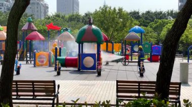 Taipei, Tayvan-04 Mayıs 2020: Covid19 güvenlik önlemleri kapsamında bir işçi Daan Park 'taki renkli bir oyun alanını dezenfekte ediyor. Şehir parkında halk sağlığı çalışmaları