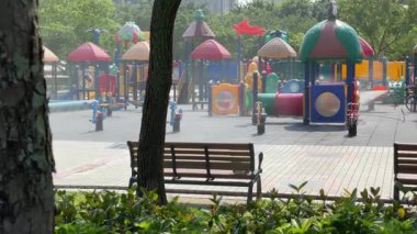 Taipei, Tayvan-04 Mayıs 2020: Bir işçi renkli bir oyun alanını ve güvenlik önlemlerini dezenfekte ediyor. Yüksek binaların arka planına sahip bir şehir parkında kamu sağlığı çalışmaları.