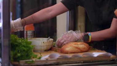 Hanoi, Vietnam-03 Nisan 2024: Tipik Banh Mi yapan bir şefin yavaş çekimi, et ve sebzeli bir sandviç, bir baget Vietnam mutfağını Fransız mutfağıyla birleştirdi