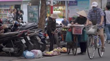 Hanoi, Vietnam-04 Nisan 2024: Bisikletli iki Vietnamlı sokak satıcısı Hanoi şehrinde bir yol boyunca seyyar gıda tezgahına dönüştü. Vietnam Kültür Mirası.