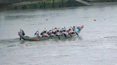Taipei, Tayvan-08 Haziran 2024: Taipei ejderha botu yarışının yavaş hareketi kıyıdan alınan senkronize raketlerle, öğleden sonra güneş altında her vuruşta sıçrama ve kas gerilimi gösteriyor.