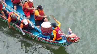Taipei, Tayvan-08 Haziran 2024: Yavaş hareket eden Taipei kürekçisi bacaklarının üzerinde dinlenen kürekle, huzurlu bir sahne ve yumuşak yansımalarla nehirde süzülüyor.
