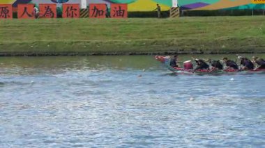 Taipei, Tayvan-08 Haziran 2024: Altın günbatımı ışığı suya yansıdıkça, Taipei kürekçisinin odak ile yavaşça ilerlemesi, profil olarak filme alınması.