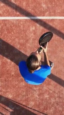 Dikey, dış sahada raket oynayan bir adamın yukarıdan görünüşü. Spor yapma kavramı.
