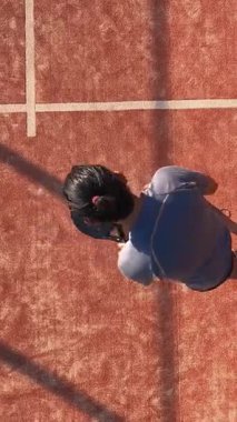 Dış sahada tenis oynamak için topa vuran bir adamın dikey ve tepeden görünüşü. Spor yapma kavramı.