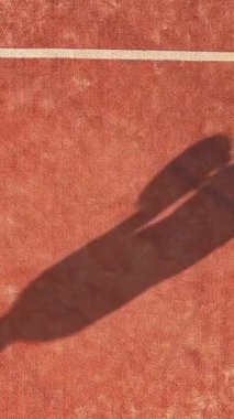 Dikey olarak, Shadow açık sahada raket oynayan birinin üstünden görüldü. Padel maçı veya turnuva.