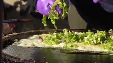 Tayvan 'ın Taichung kentindeki sokak pazarında gece boyunca spatulayla çevrilen istiridye omletinin yavaş çekimleri.