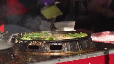 Gece pazarında, Taichung 'daki bir yiyecek standında istiridye karışımının üzerine yavaşça yumurta kırılması.