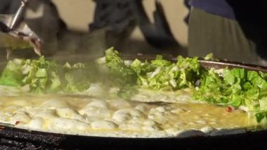 Tayvanlı sokak satıcısının yavaş çekimde yaptığı sos, Taichung gece pazarında yeni pişmiş istiridye omletinin üzerine dökülüyor.