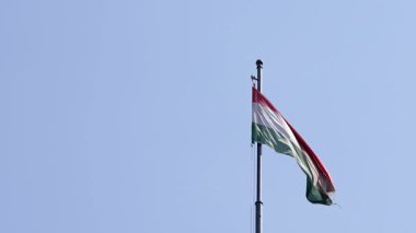 Macaristan bayrağının açık bir Budapeşte gökyüzüne karşı yüksek bir direkte sallanışı, barış dolu bir ortamda ulusun gurur ve mirasını somutlaştırıyor..