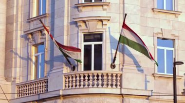Budapeşte 'de zarif bir binanın cephesinde gün batımında sallanan Macar bayrakları akşam havasını ve ulusal gururu yakalıyor..