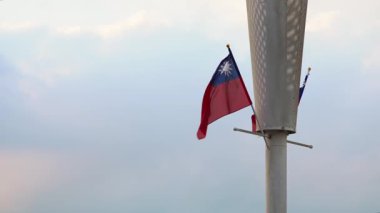 Hafif bulutlu bir gökyüzüne dikilmiş Tayvan bayrağının rüzgarda dalgalanması. Özgürlük, kültür ve ulusal gurur temaları için mükemmel..