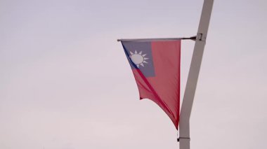 Tayvan bayrağının yavaşça dalgalanması açık gökyüzüne karşı, özgürlüğü ve ulusal gururu temsil ediyor..