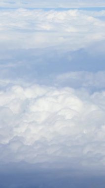 Uçsuz bucaksız mavi gökyüzünü ve ufuk boyunca uzanan beyaz bulutları gösteren dikey çekim Dünya atmosferinin güzelliğini vurguluyor..