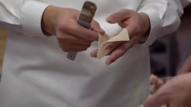 Tayvan şeflerinden oluşan bir takımın geleneksel yemekleri yavaş çekimde pişirmesi. Asyalı şef Tayvan restoranında taze börek yapıyor. Erkekler elleriyle hamur köftesi pişirir ve hazırlarlar..
