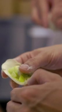 Tayvanlı şeflerden oluşan dikey ekip geleneksel hamur köftelerini ustalıkla hazırlıyor, elleri hamuru ustalıkla şekillendiriyor. Kalabalık bir restoranda şefler taze ve otantik tatlar yaratırlar..