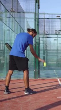 Açık havada tenis oynayan bir adamın dikey, üstten çekimi. Padel yarışmasına hazırlanıyor..