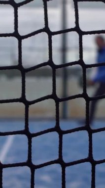 Mavi kortta oynayan raket tenisçisinin ızgara görüntüsünde yavaş çekim. Kafkas raket oyuncusu bir sporcu topa vuruyor. Raket sporu kavramı.