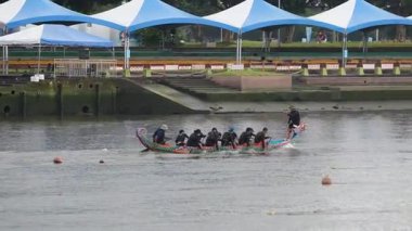 Taipei, Taipei, Tayvan-08 Haziran 2024: Taipei 'de ejderha botu yarışındaki kadın raketçinin yavaş hareketi, güneşli festival gününde güç, ritim ve çaba göstermesi ve arka planda kalabalıkla birlikte.