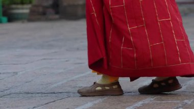 Tapınakta yürüyen Budist rahibin yavaşlığı. Ruhani atmosferde ritmik adım atan geleneksel ayakkabılara odaklan..
