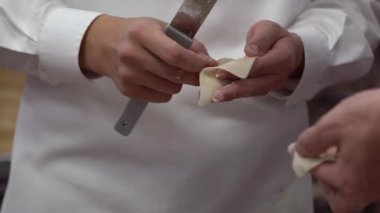 Tayvan şeflerinden oluşan bir takımın geleneksel yemekleri yavaş çekimde pişirmesi. Asyalı şef Tayvan restoranında taze börek yapıyor. Erkekler elleriyle hamur köftesi pişirir ve hazırlarlar..