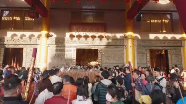 Taichung, Tayvan-29 Ocak 2025: Tayvan tapınağı, ibadet eden kalabalık kırmızı perdeler ve altın arka plan ışığı altında tütsüyle dua ediyor. Kültürel ve ruhsal unsurlar canlı kolektif ayinlerle harmanlanır..