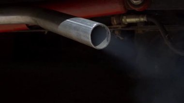 Yavaş çekimde ağır beyaz dumanın otomobil egzoz borusundan kaçarak zehirli karbon monoksit salınımına yol açması. Yoldaki araç emisyonları, şehir trafiğinde hava kirliliği sorunu
