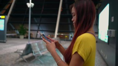 Modern havaalanında akıllı telefona bakan biri. Arka planda havaalanı içeriği, sergilenen seyahat ve teknoloji yer alıyor. Teknoloji veya ulaşım konuları için mükemmel.