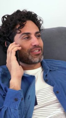 Mutlu gülümseyen adam evdeki koltukta otururken akıllı telefon kullanıyor. Olgun bir adam koltukta uzanıp cep telefonundan mesajlar okuyor. Beyaz İspanyol adam evde dinleniyor..