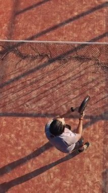 Dış sahada raket tenis teknikleri uygulayan birinin dikey ve tepeden çekimi. Devamlı raketle topa vuruyor..