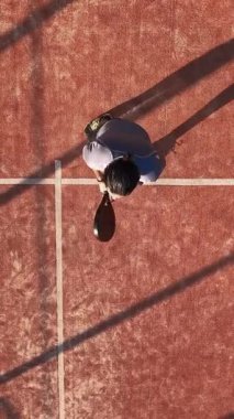 Dikey, açık alanda tenis oynayan genç bir adamın yukarıdan çekimi. Spor yapma kavramı.