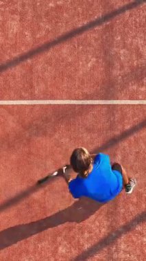 Dış sahada maç yapan profesyonel bir raket tenisçisinin dikey ve üst görünümü.