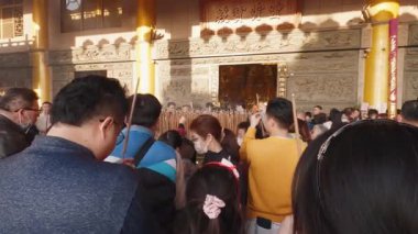 Taichung, Tayvan-29 Ocak 2025: Tayvan tapınağında sunağa bakarken elinde tütsü tutan tapınmacılar. Çevredeki sıcak ışık kutsal ortamda barışçıl, müşterek ruhani anı iletir..