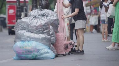 Güney Kore, Seul -08 Temmuz 2025: Yavaş insanlar Insadong yaya caddesinde büyük geri dönüşüm çantalarının yanından geçmekte, arka planda mağazalar ve hafif yaz kıyafetleriyle yerel halkın yavaş trafiği ile birlikte