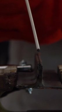 Slowmotion of metal processing with a man using welding machine for steel seam. Locksmith in special clothes and gloves to works in production. Sparks in metalworking.