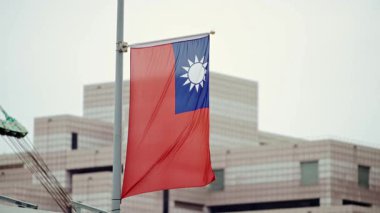 Modern bir binanın girişinde sergilenen Tayvan bayrağının yavaş hareketi, kentsel bir ortamda ulusal gururu vurguluyor.