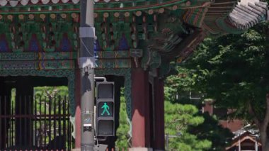 Güney Kore, Seul - 10 Temmuz 2025: Renkli ahşap mimariyle geleneksel Kore kapısının önündeki ışıklı yaya geçidi yavaş hareket ediyor