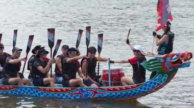 Taipei, Tayvan-08 Haziran 2024: Sessizce süzülen Taipei kürekçisinin yavaş hareketi, dizlerinin üzerinde dinlenen kürek, sakin göl üzerinde yansıyan arka ışık.