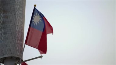 Tayvan bayrağının açık bir gökyüzüne doğru yavaşça dalgalanması. Vatanseverlik, ulusal kimlik ve kültürel gurur için ideal.