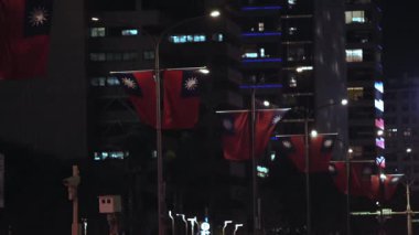 Gece şehir ışıkları altında sokak direklerinde sallanan birden fazla Tayvan bayraklarının yavaş hareket etmesi ulusal bir gurur hissi uyandırıyor..