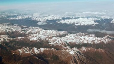 Karla kaplı Alpler 'in hava manzarası, engebeli dağ zirveleri manzarayı kapsıyor. Yüksek rakımlar hafif kar tozlarıyla kaplı, dağlara buzlu bir görünüm kazandırıyor..